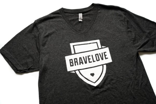 A black V-neck t-shirt with a shield logo and the word "BRAVELOVE" in bold white letters across the front.