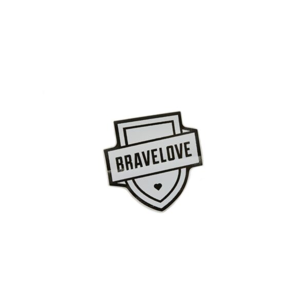 A bumper sticker designed with a black and white badge that has the word "BRAVELOVE" across a shield shape, featuring a small heart at the bottom center.