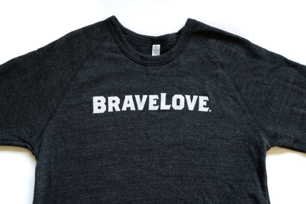 A charcoal grey sweatshirt with the word "BRAVELOVE" printed in bold, white, uppercase letters on the front.