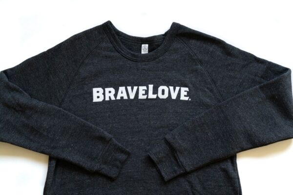 A charcoal grey sweatshirt with the word "BRAVELOVE." printed in white letters across the chest, with sleeves spread out on both sides.