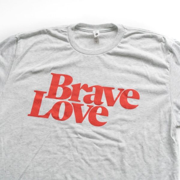 Introducing the New! BraveLove T-Shirt: a stylish gray tee featuring bold red text that reads "Brave Love," showcased on a pristine white background.