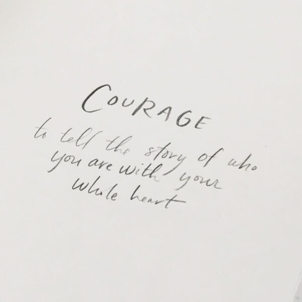 Handwritten text reads, "Courage to tell the story of who you are with your whole heart" in a BraveLove Journal.