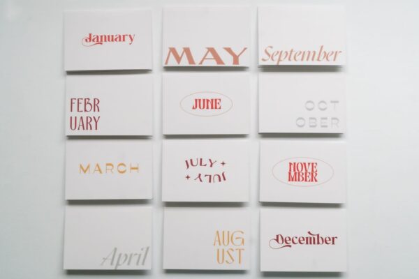 A grid of 12 white square cards from the New! Months of the Year Stationary Set, featuring the months of the year written in an assortment of fonts and colors.