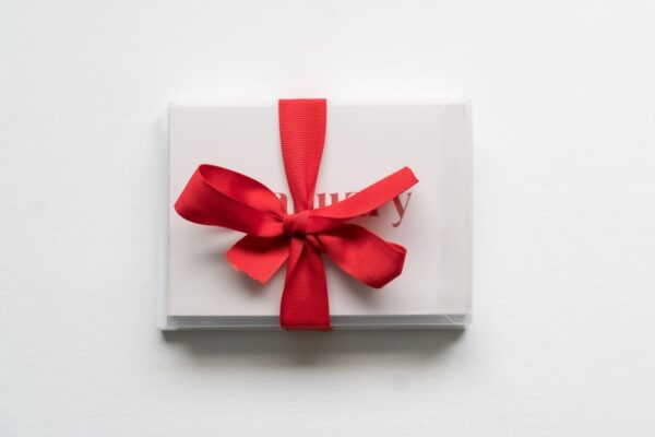 A New! Months of the Year Stationary Set wrapped with a red ribbon bow, containing a card with partially visible red text on a white background.