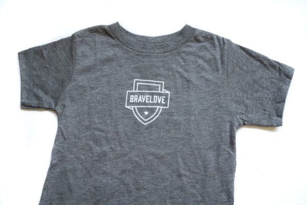 Product Description: New! Toddler T-Shirt in Grey featuring the "BRAVELOVE" shield logo centered on the chest, displayed against a white background.