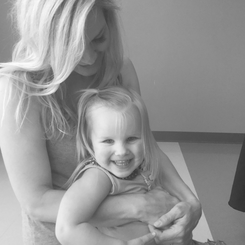 A woman smiling and holding a laughing young girl in her arms. The image is in black and white.