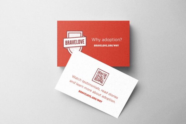 Two "Why Adoption? Pocket Notecards" on a grey background, one red and one white, featuring text and a QR code about adoption from Bravelove.org.