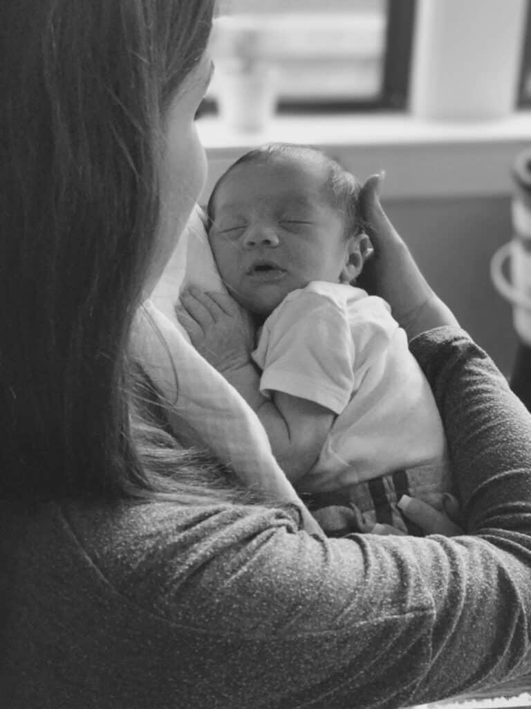 A woman lovingly cradles a sleeping newborn baby close to her chest in a calm and serene moment.