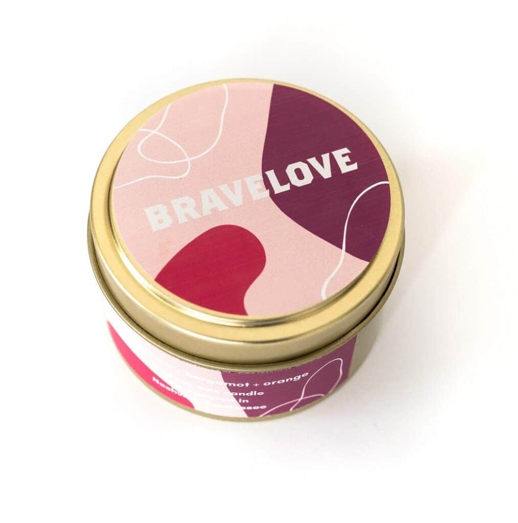 Circular tin container with a pink and red abstract design on the lid, labelled "BRAVELOVE.